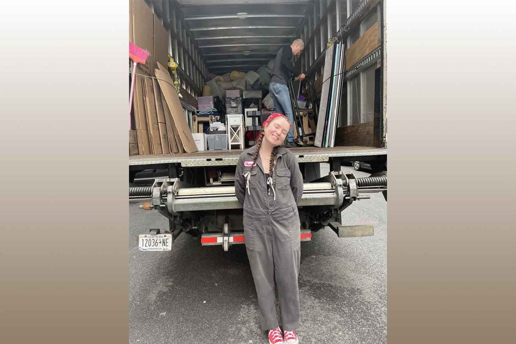 Shannon Hughes stands in front of a moving truck.