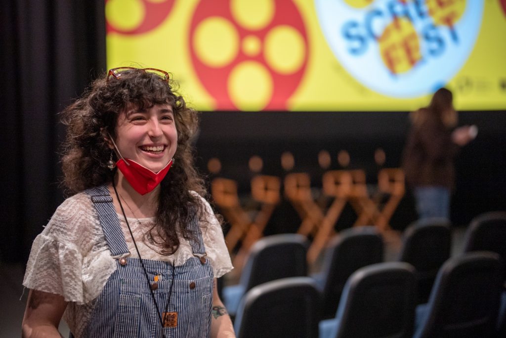 A student smiles in a film auditorium.