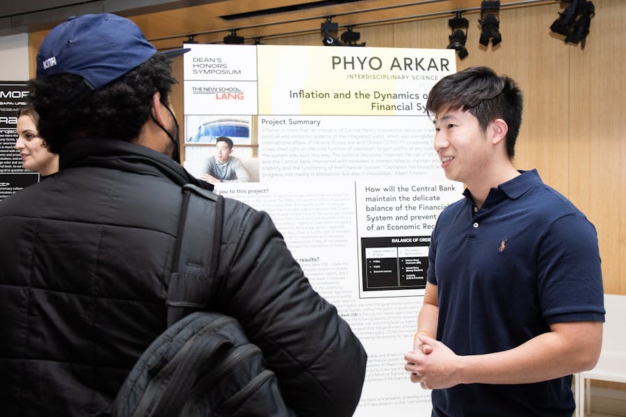 Phyo Arkar discusses his poster project with an attendee at the Dean's Honor Symposium